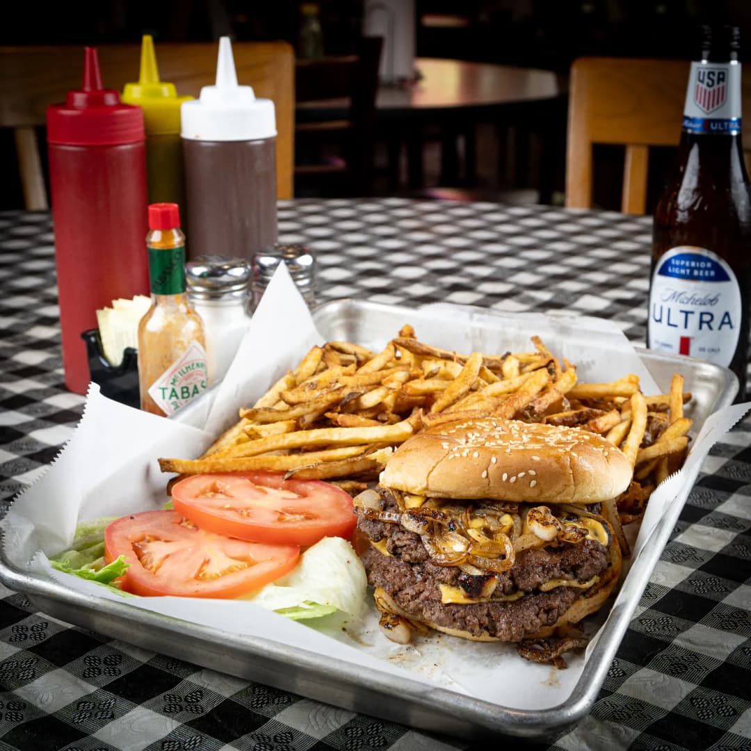A smash burger with griddled onions in a tray with fries, lettuce and tomato at Sammies Bar-B-Q in Fort Worth, TX